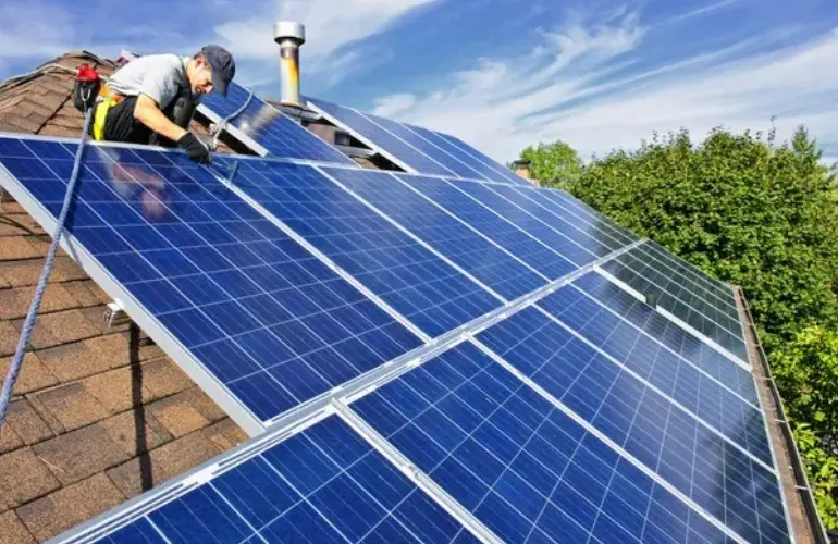 A man working on solar panels on the roof of a house.